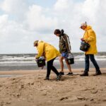 Mensen op het strand in gele jassen