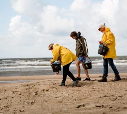 Mensen op het strand in gele jassen