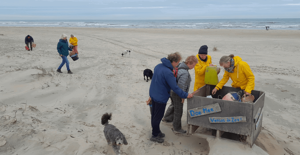 Mensen en een hond op het strand om een houden bak met tekst Doe mee Verlos de Zee