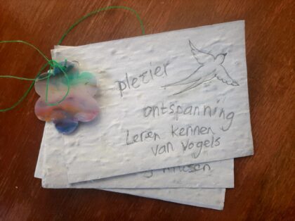 3 briefjes samengebonden met een plastic draadje en een bloemetje met op het blaadje de woorden plezier, ontspanning en leren kennen van vogels.