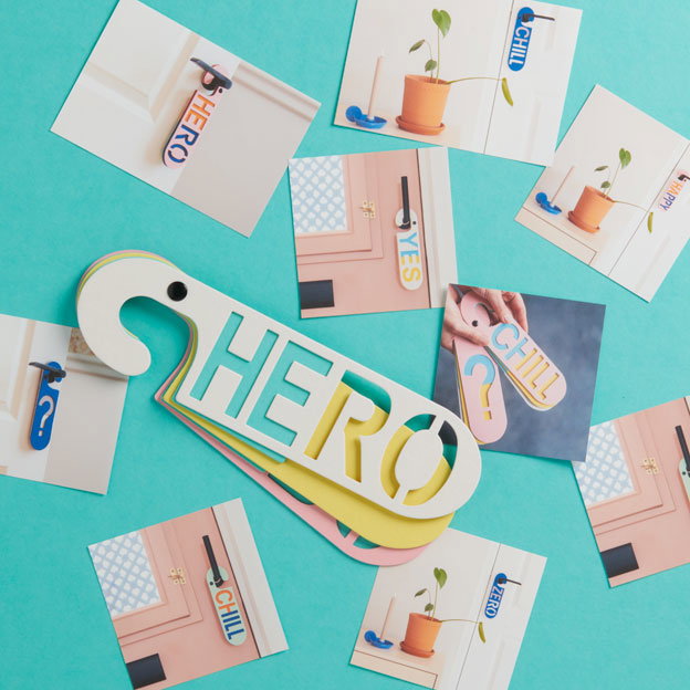 Witte deurhanger met het woord Hero op een turquoise achergrond met foto's