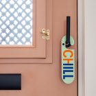 Terracotta kleurige voordeur met licht groene deurhanger met het woord chill